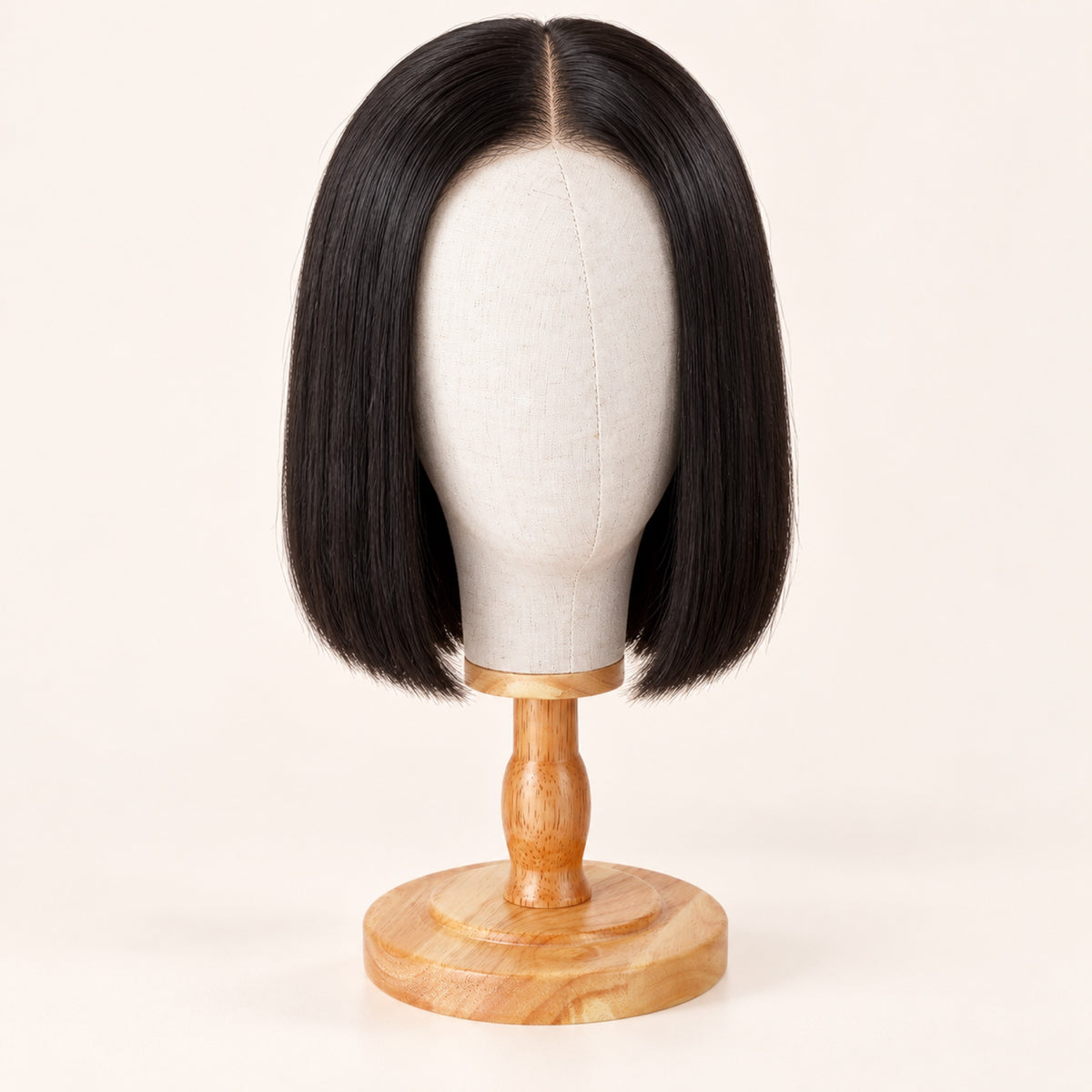 Tête porte-perruque en toile sur socle en bois, avec une perruque carré lisse noire posée dessus